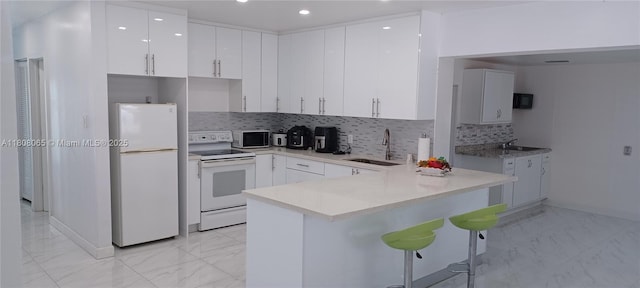 650 E 55th St, Hialeah, FL 33013 - kitchen featuring white appliances, light marble finish floors, a peninsula, a breakfast bar area, and recessed lighting