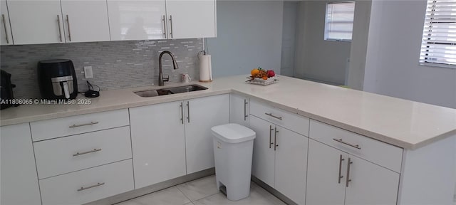 650 E 55th St, Hialeah, FL 33013 - kitchen with light countertops, decorative backsplash, white cabinets, and a peninsula