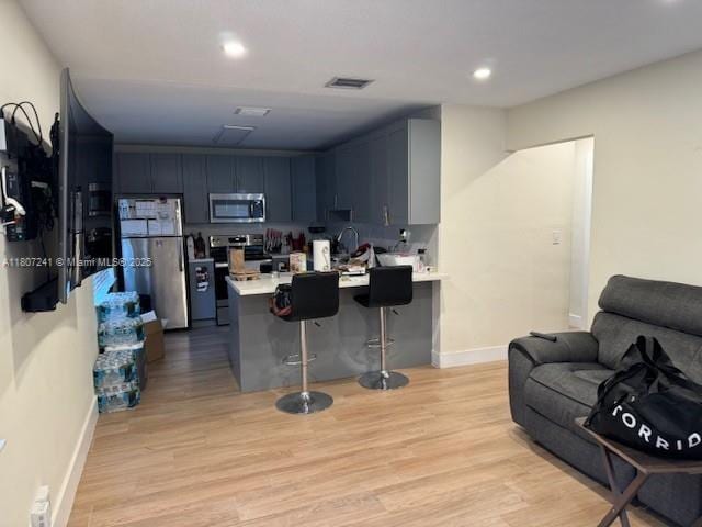 6121 SW 40th Ct, Miramar, FL 33023 - kitchen with stainless steel appliances, a peninsula, light countertops, open floor plan, and light wood-style flooring