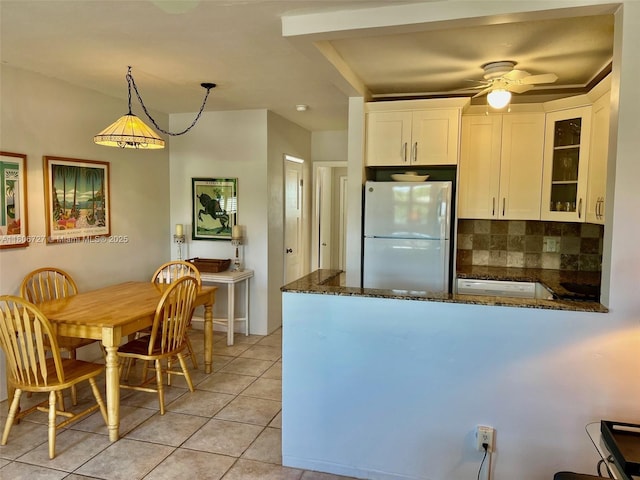 301 E Mcnab Rd Unit 205, Pompano Beach, FL 33060 - kitchen featuring freestanding refrigerator, dark stone counters, white cabinetry, decorative backsplash, and a peninsula