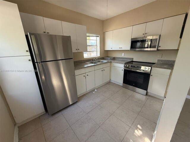 1025 NW 3rd Ave, Fort Lauderdale, FL 33311 - kitchen featuring appliances with stainless steel finishes, a sink, light tile patterned flooring, and dark countertops