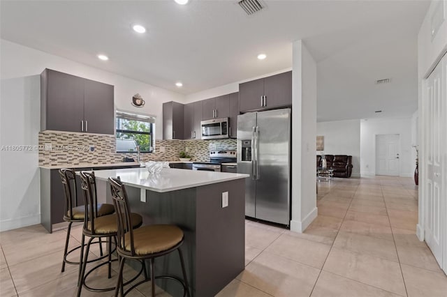 32004 SW 199th Ct, Homestead, FL 33030 - kitchen with appliances with stainless steel finishes, a breakfast bar, backsplash, light countertops, and a center island