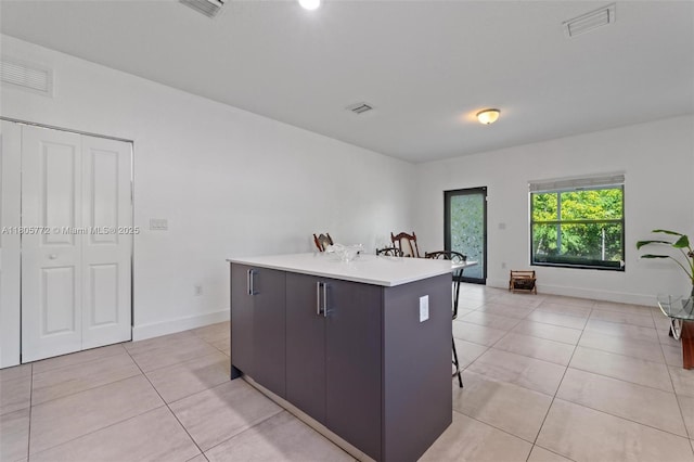 32004 SW 199th Ct, Homestead, FL 33030 - kitchen featuring a kitchen island, a breakfast bar, light tile patterned floors, light countertops, and baseboards