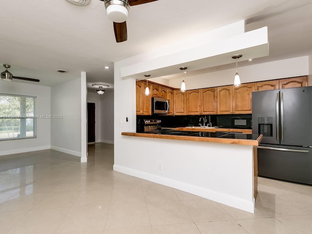 870 NE 182nd St, North Miami Beach, FL 33162 - kitchen with appliances with stainless steel finishes, ceiling fan, light tile patterned floors, a peninsula, and baseboards