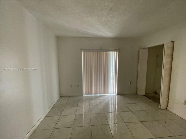 8670 NW 6th Ln Unit 4-103, Miami, FL 33126 - empty room with a textured ceiling, light tile patterned floors, and baseboards