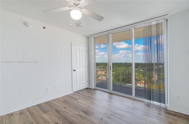 2665 SW 37th Ave Unit 906, Miami, FL 33133 - empty room featuring a wall of windows, wood finished floors, a ceiling fan, a smoke detector, and baseboards