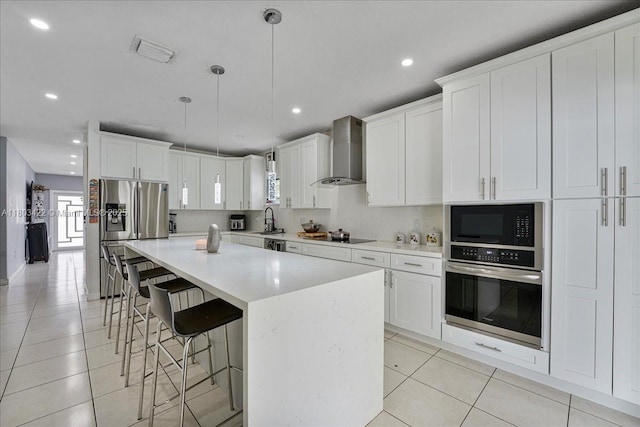 810 NW 112th St, Miami, FL 33168 - kitchen with stainless steel appliances, wall chimney range hood, light tile patterned floors, a kitchen bar, and recessed lighting