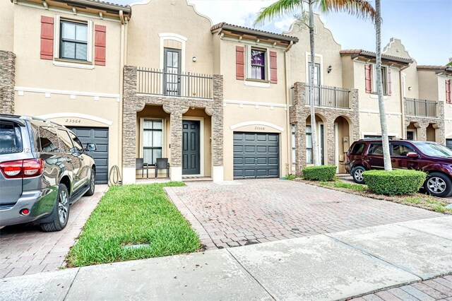 23558 SW 113th Psge, Homestead, FL 33032 - view of property with decorative driveway, a garage, stucco siding, stone siding, and a balcony