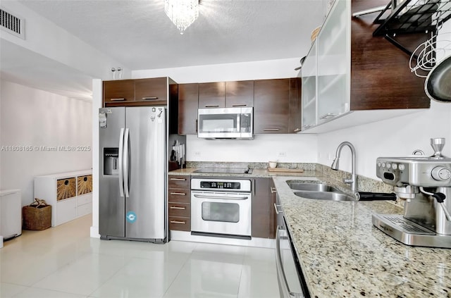 41 SE 5th St Unit 1012, Miami, FL 33131 - kitchen with appliances with stainless steel finishes, a sink, dark brown cabinetry, light stone counters, and a textured ceiling