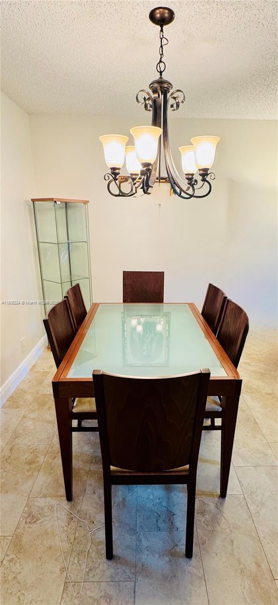 14360 Strathmore Ln Unit 102, Delray Beach, FL 33446 - dining space featuring a textured ceiling and a chandelier