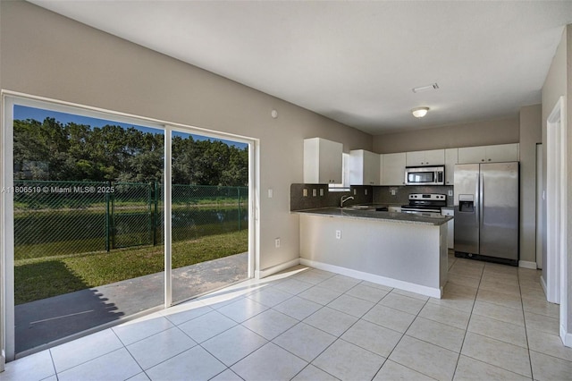 1880 SE 3rd Dr, Homestead, FL 33033 - kitchen with stainless steel appliances, light tile patterned flooring, white cabinetry, a peninsula, and tasteful backsplash