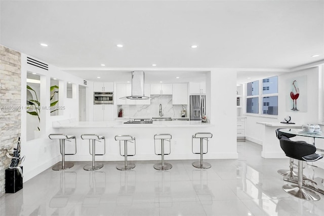 2751 S Ocean Dr Unit 301S, Hollywood, FL 33019 - kitchen featuring appliances with stainless steel finishes, wall chimney range hood, a kitchen breakfast bar, white cabinets, and recessed lighting