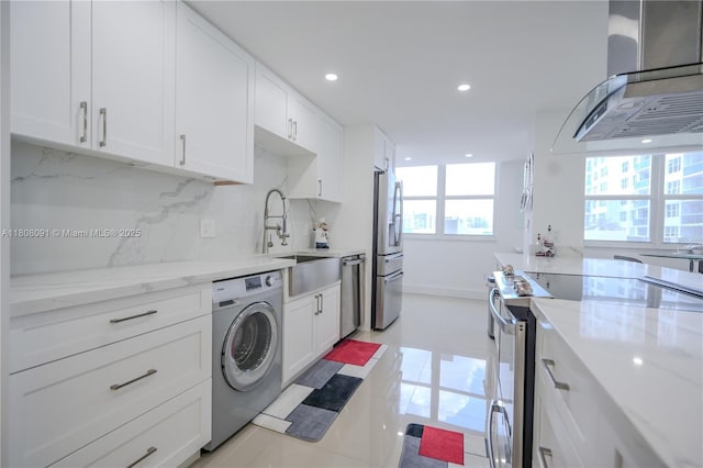 2751 S Ocean Dr Unit 301S, Hollywood, FL 33019 - kitchen with washer / clothes dryer, wall chimney exhaust hood, stainless steel appliances, tasteful backsplash, and white cabinetry