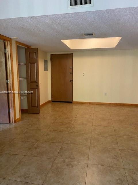 8004 SW 149th Ave Unit C102, Miami, FL 33193 - empty room featuring a textured ceiling, light tile patterned floors, and baseboards