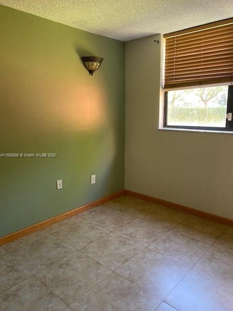 8004 SW 149th Ave Unit C102, Miami, FL 33193 - tiled spare room featuring a textured ceiling and baseboards