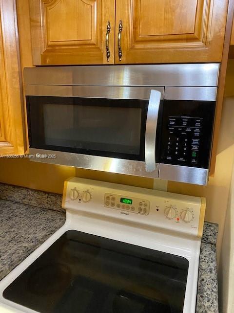 8004 SW 149th Ave Unit C102, Miami, FL 33193 - kitchen view of stainless steel microwave, electric range, and brown cabinetry