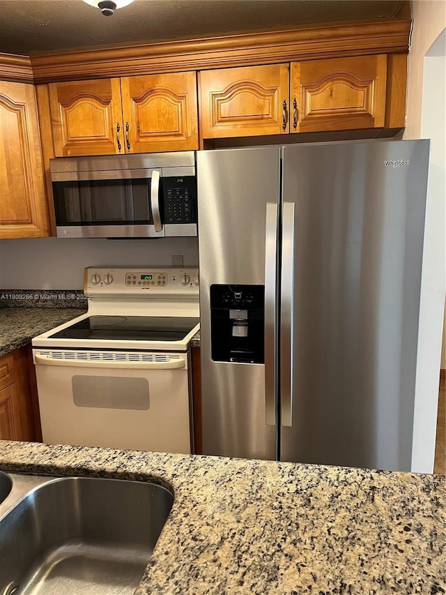 8004 SW 149th Ave Unit C102, Miami, FL 33193 - kitchen featuring appliances with stainless steel finishes, brown cabinetry, and light stone counters