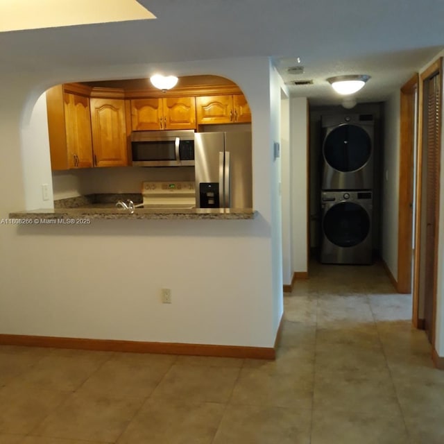 8004 SW 149th Ave Unit C102, Miami, FL 33193 - kitchen with appliances with stainless steel finishes, arched walkways, stacked washer and clothes dryer, and a peninsula