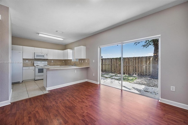 1985 SE 3rd St, Homestead, FL 33033 - kitchen featuring white appliances, a peninsula, white cabinetry, light wood-style floors, and baseboards