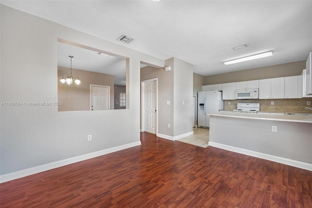 1985 SE 3rd St, Homestead, FL 33033 - kitchen with white appliances, light countertops, light wood-style floors, a peninsula, and white cabinetry