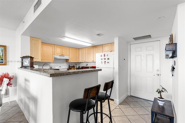 3000 Coral Way Unit 1505, Miami, FL 33145 - kitchen featuring under cabinet range hood, light brown cabinetry, freestanding refrigerator, and light tile patterned flooring