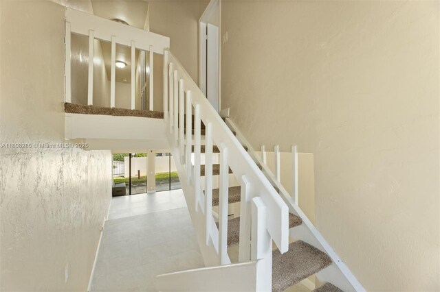 19460 NE 26th Ave Unit 12B, Miami, FL 33180 - stairway featuring a high ceiling and a textured wall