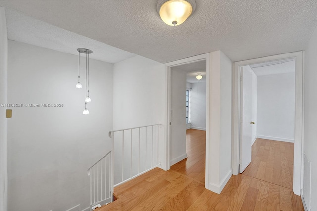1551 NW 92nd Ave Unit 185, Pembroke Pines, FL 33024 - hall with an upstairs landing, light wood-style flooring, a textured ceiling, and baseboards