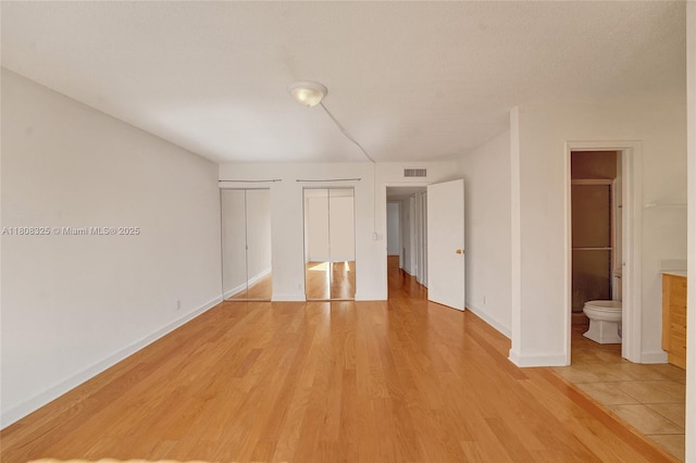 1551 NW 92nd Ave Unit 185, Pembroke Pines, FL 33024 - unfurnished bedroom with multiple closets, light wood finished floors, baseboards, and ensuite bathroom