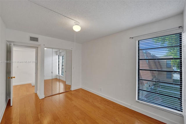 1551 NW 92nd Ave Unit 185, Pembroke Pines, FL 33024 - unfurnished bedroom with light wood-style flooring, multiple windows, a textured ceiling, a closet, and baseboards
