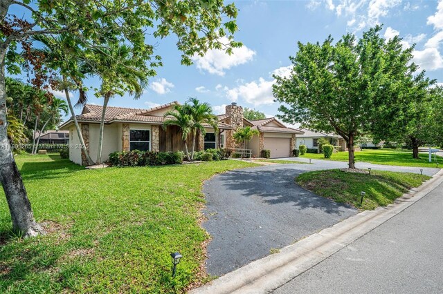 9919 SW 1st Ct, Coral Springs, FL 33071 - ranch-style home featuring stone siding, driveway, a garage, and a front lawn