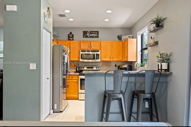 3427 W 89th Ter, Hialeah, FL 33018 - kitchen featuring appliances with stainless steel finishes, a breakfast bar, a peninsula, light tile patterned floors, and recessed lighting