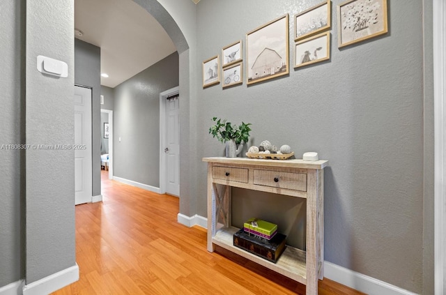 3427 W 89th Ter, Hialeah, FL 33018 - corridor featuring arched walkways, light wood-style floors, a textured wall, and baseboards