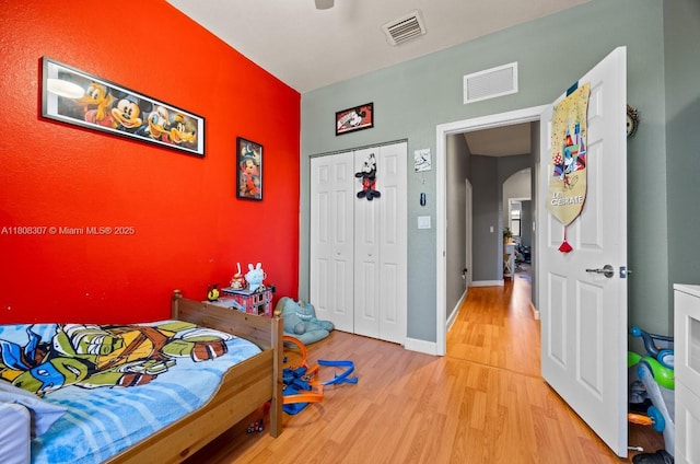 3427 W 89th Ter, Hialeah, FL 33018 - bedroom with light wood finished floors, arched walkways, a closet, an accent wall, and baseboards