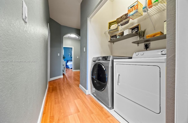 3427 W 89th Ter, Hialeah, FL 33018 - washroom featuring washer and dryer, arched walkways, light wood finished floors, a textured wall, and baseboards