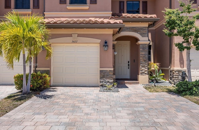3427 W 89th Ter, Hialeah, FL 33018 - view of front of house featuring stone siding, a garage, stucco siding, a tiled roof, and decorative driveway