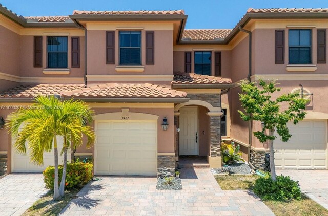 3427 W 89th Ter, Hialeah, FL 33018 - view of front of home with an attached garage, a tile roof, stone siding, and decorative driveway