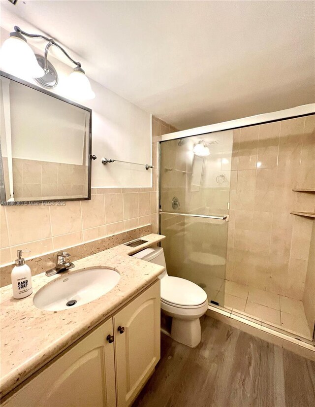 8233 Harding Ave Unit 204, Miami Beach, FL 33141 - bathroom with tile walls, wood finished floors, vanity, toilet, and a stall shower