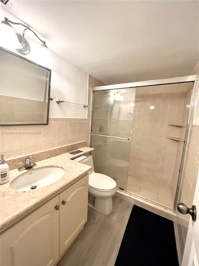8233 Harding Ave Unit 204, Miami Beach, FL 33141 - full bathroom featuring wood finished floors, tile walls, toilet, vanity, and a stall shower