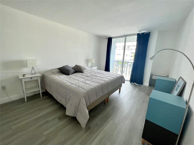 8233 Harding Ave Unit 204, Miami Beach, FL 33141 - bedroom with wood finished floors, a wall of windows, baseboards, a textured ceiling, and access to exterior