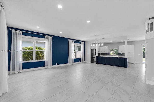 9192 Picot Ct, Boynton Beach, FL 33472 - unfurnished living room with a chandelier, baseboards, recessed lighting, and light marble finish flooring