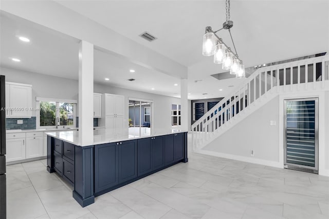 9192 Picot Ct, Boynton Beach, FL 33472 - kitchen featuring beverage cooler, white cabinetry, recessed lighting, a sink, and decorative light fixtures