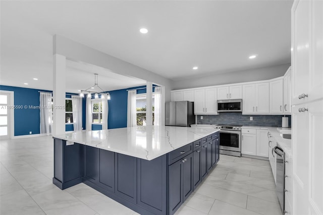 9192 Picot Ct, Boynton Beach, FL 33472 - kitchen with stainless steel appliances, white cabinets, a spacious island, light stone counters, and plenty of natural light