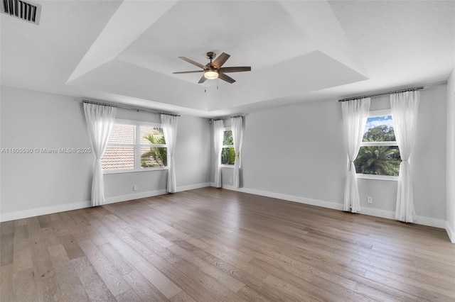 9192 Picot Ct, Boynton Beach, FL 33472 - spare room featuring a tray ceiling, ceiling fan, wood-type flooring, and baseboards