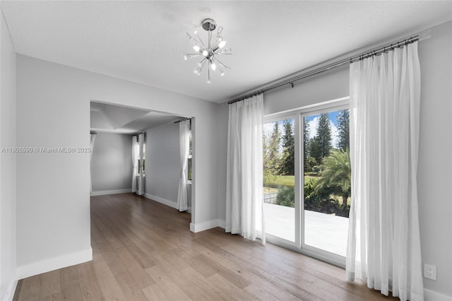 9192 Picot Ct, Boynton Beach, FL 33472 - empty room featuring a chandelier, light wood-type flooring, and baseboards
