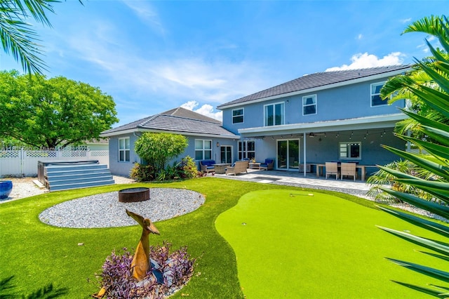 9192 Picot Ct, Boynton Beach, FL 33472 - rear view of house with an outdoor living space with a fire pit, stucco siding, a patio, and a putting area