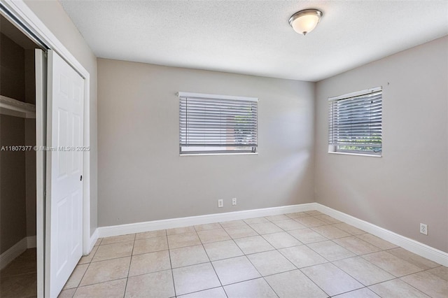 2240 NW 47th Ter, Lauderhill, FL 33313 - unfurnished bedroom with a closet, light tile patterned floors, baseboards, and a textured ceiling