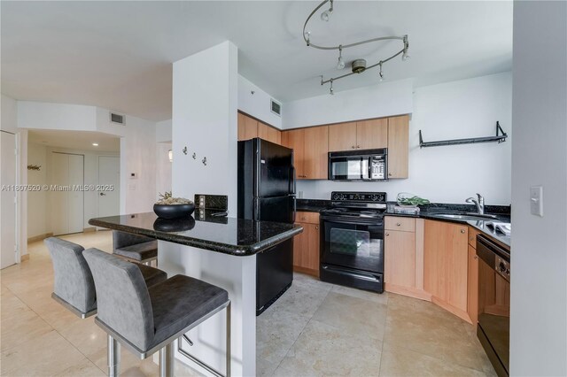 1330 W Ave Unit 902, Miami Beach, FL 33139 - kitchen featuring black appliances, a sink, a kitchen bar, light tile patterned floors, and dark stone counters