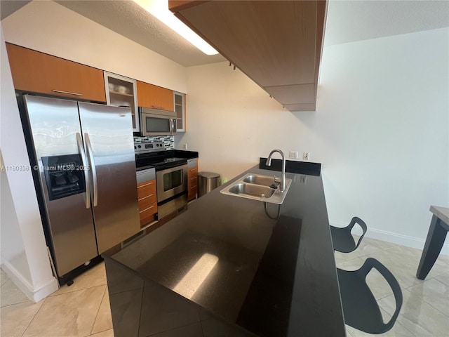 1750 N Bayshore Dr Unit 1410, Miami, FL 33132 - kitchen featuring stainless steel appliances, a sink, brown cabinetry, dark countertops, and decorative backsplash