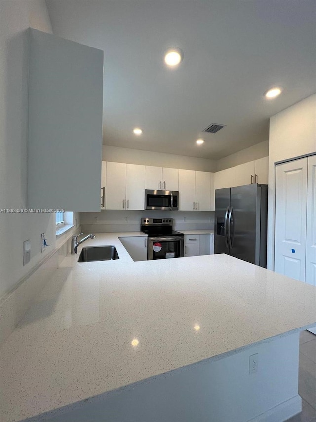 11965 NW 47th Mnr, Coral Springs, FL 33076 - kitchen with appliances with stainless steel finishes, a sink, recessed lighting, a peninsula, and white cabinets
