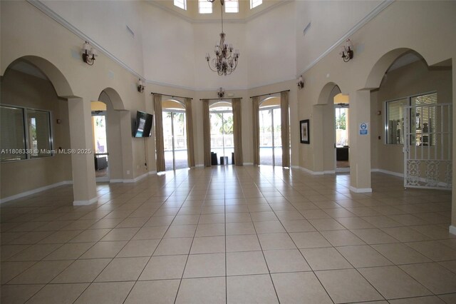 3045 SW 129th Way Unit 152, Miramar, FL 33027 - empty room featuring light tile patterned flooring, baseboards, a towering ceiling, arched walkways, and a chandelier